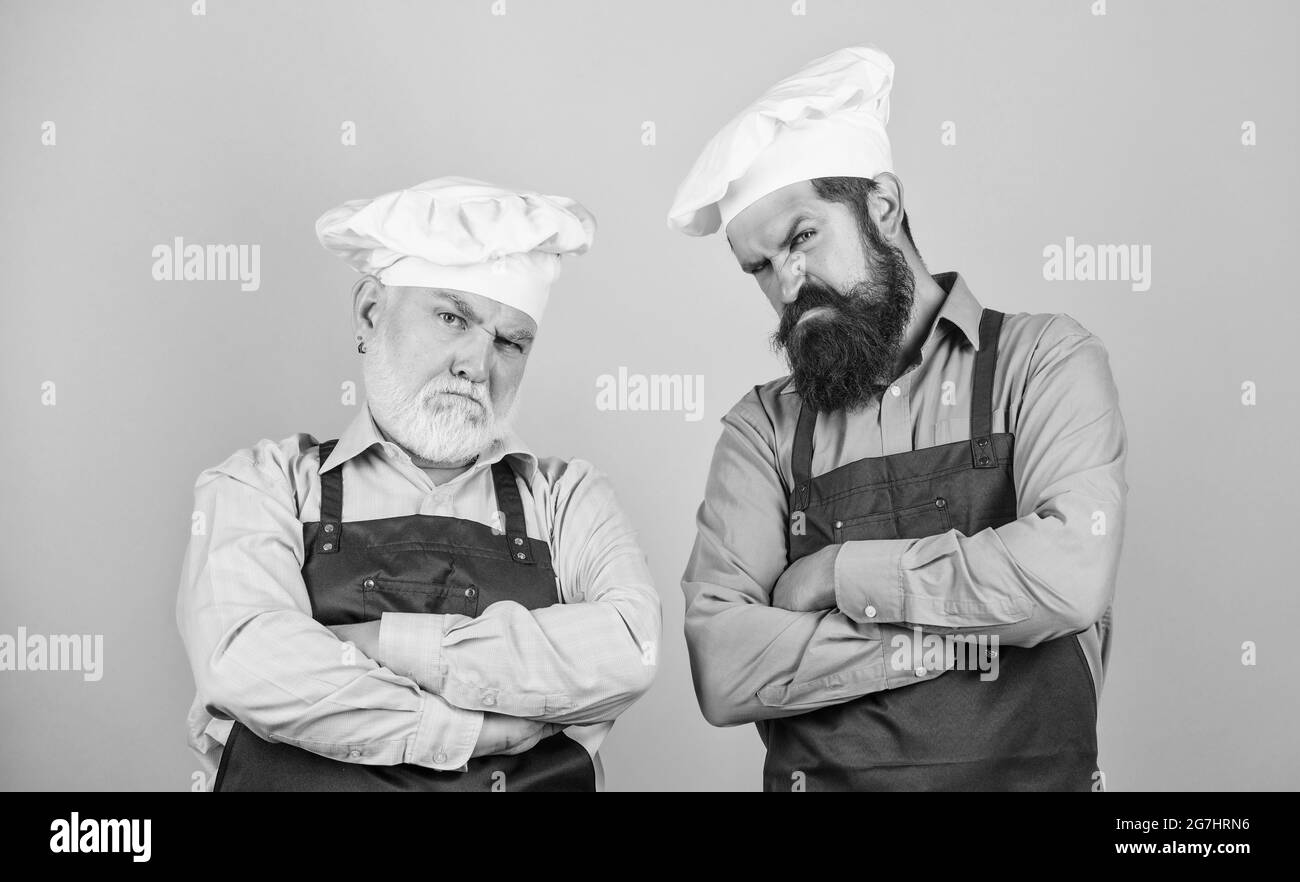 Culinary battle. Mature bearded men professional restaurant cooks competitors. Culinary show. Chef men wear aprons. Father and son culinary hobby Stock Photo