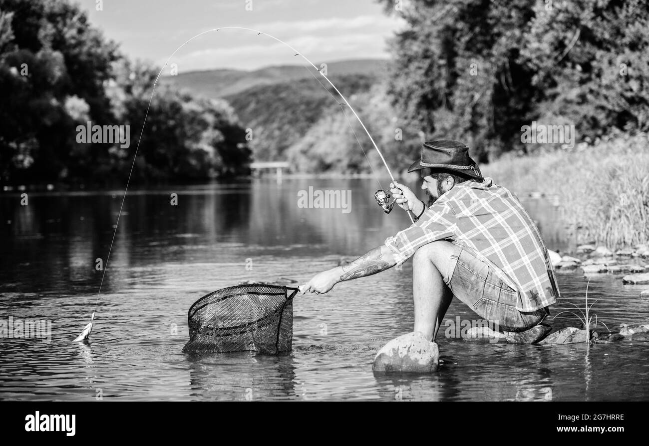 Making me happy. mature bearded man with fish on rod. successful fisherman in lake water. hipster fishing with spoon-bait. fly fish hobby of man Stock Photo