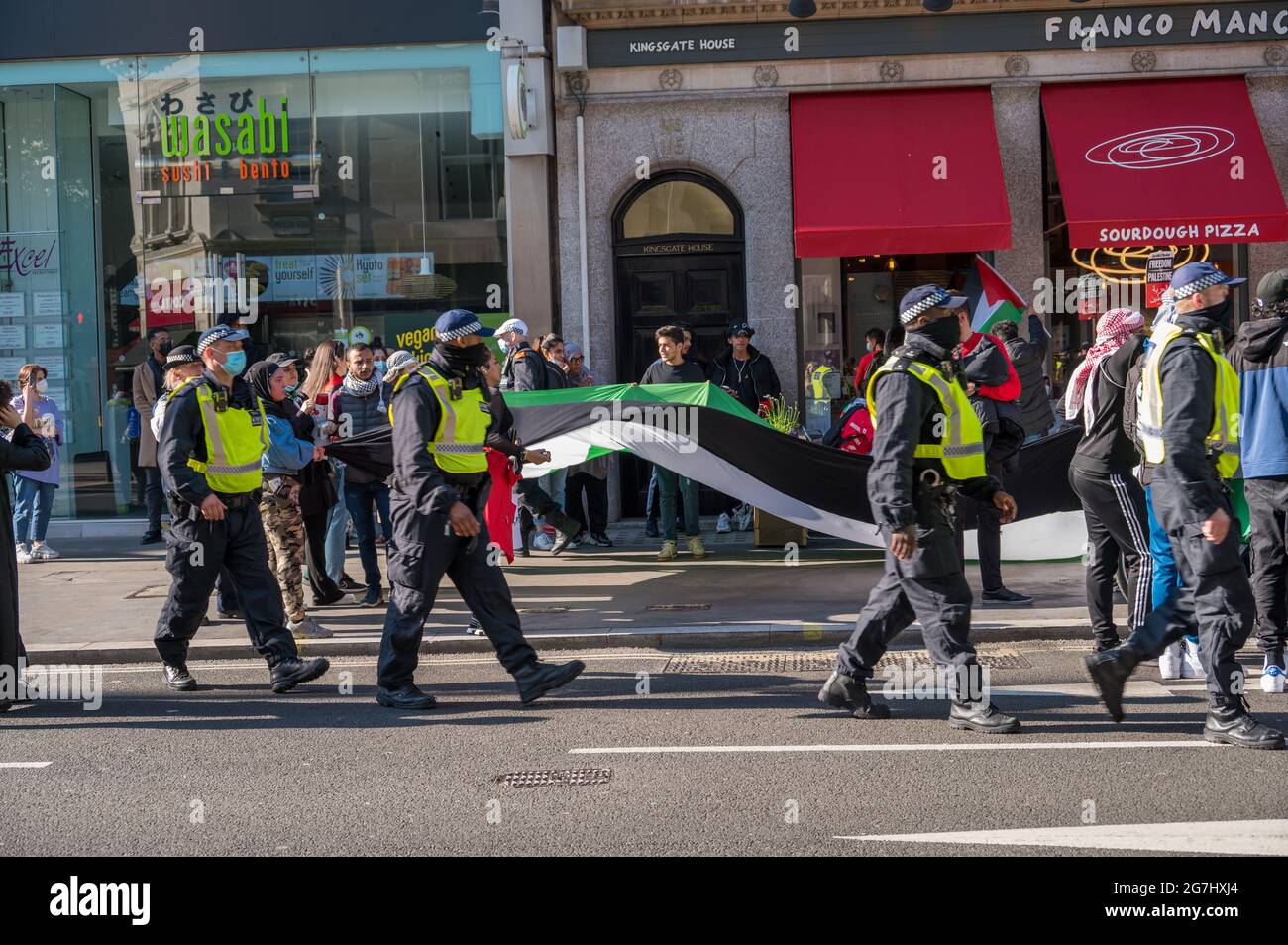 LONDON - MAY 29, 2021: British police officers walk alongside protesters at a Freedom for Palestine protest rally in London Stock Photo