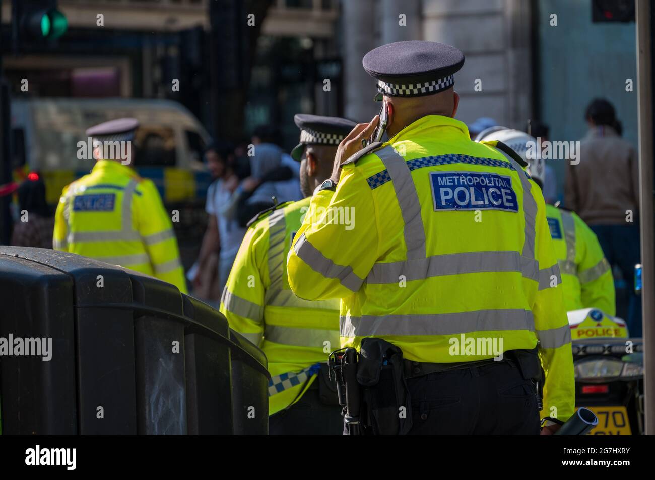LONDON - MAY 29, 2021: British police officer in a high visibility jacket uses a mobile cell phone Stock Photo