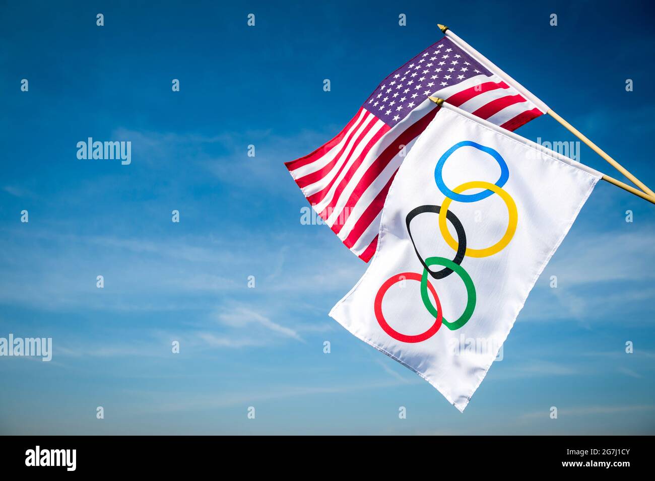 RIO DE JANEIRO - MARCH, 2016: An Olympic flag hangs together with a US stars and stripes flag under bright blue sky. Stock Photo