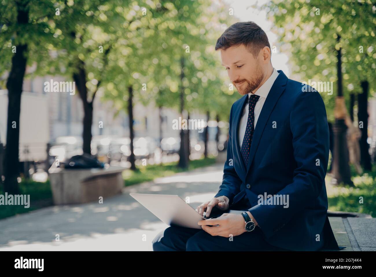 Businessman sitting on bench park working on laptop hi-res stock ...