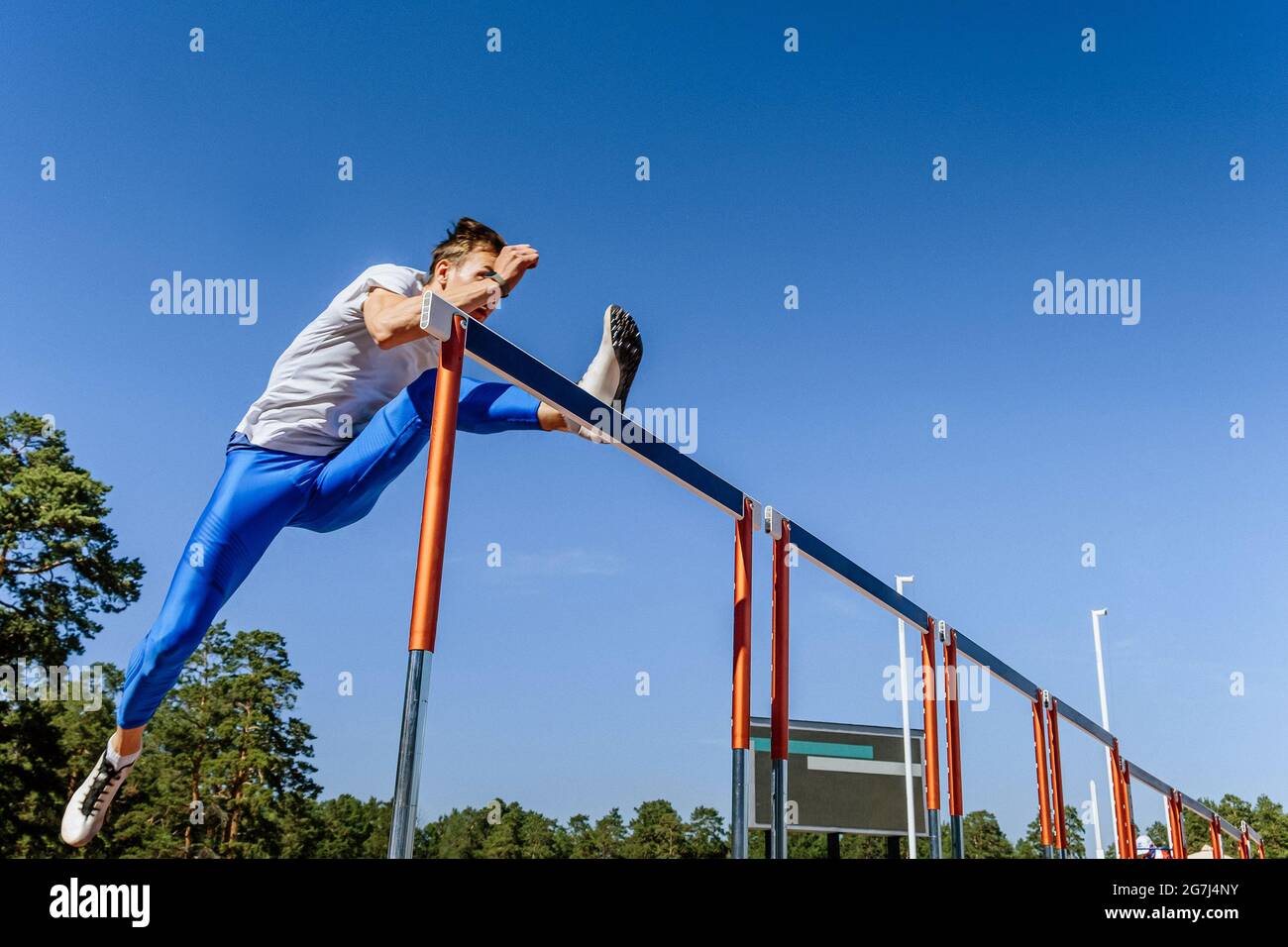 male athlete run 110 meters hurdles at track and field competition