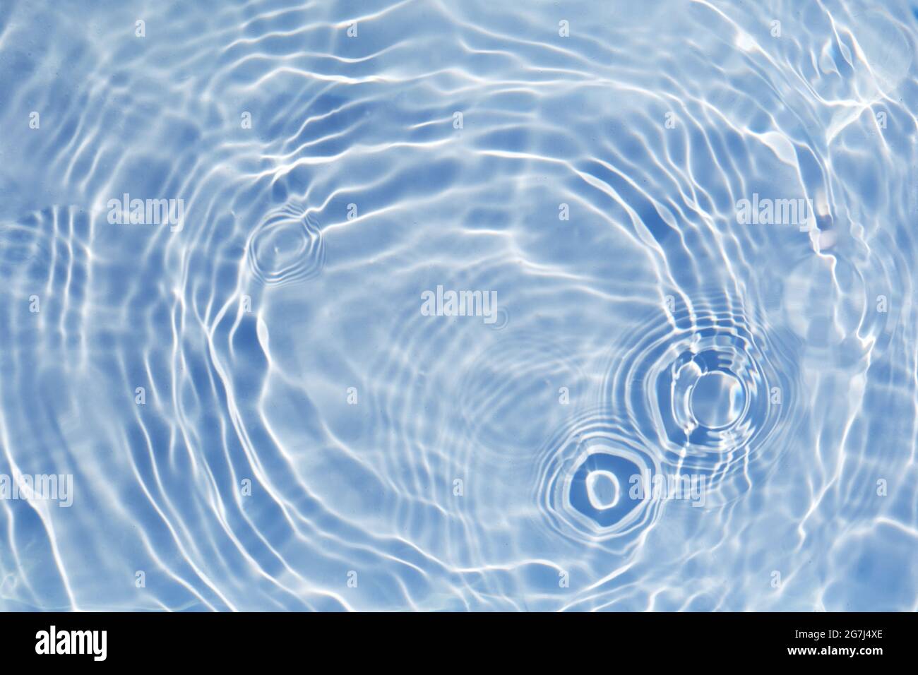 Blue clear water surface texture with splashes and bubbles. Trendy abstract water background. Water waves in sunlight. Stock Photo