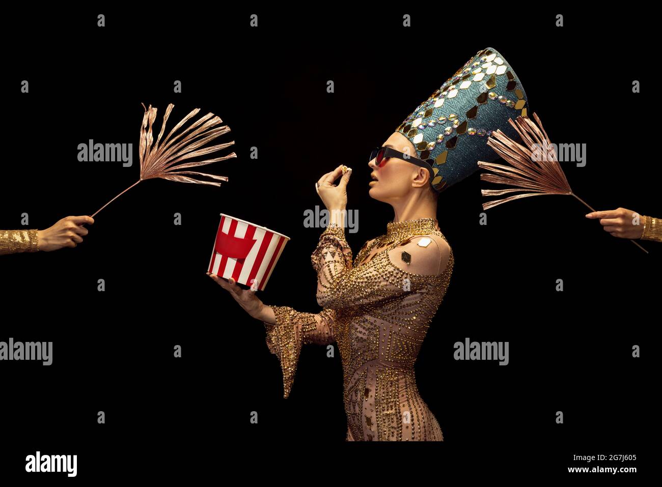 One young woman in image of Nefertiti in art performance watching movie isolated on dark background. Retro style, comparison of eras, humor concept. Stock Photo
