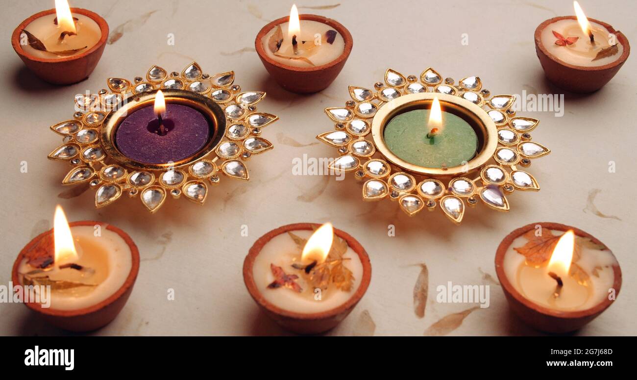 Two sunlike and other candle holders with burning candles on white