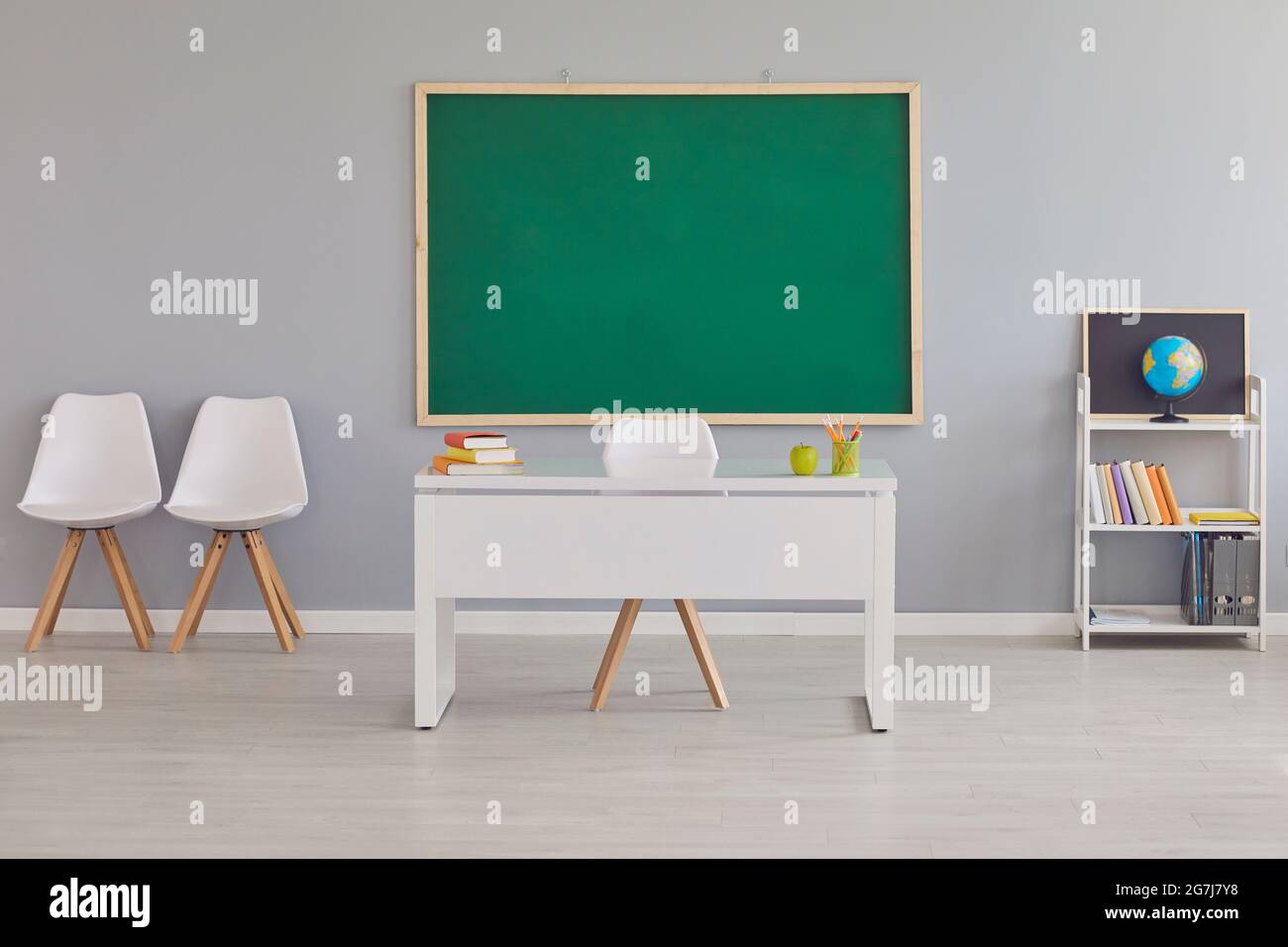 Interior of modern school classroom with teacher's desk and clean green