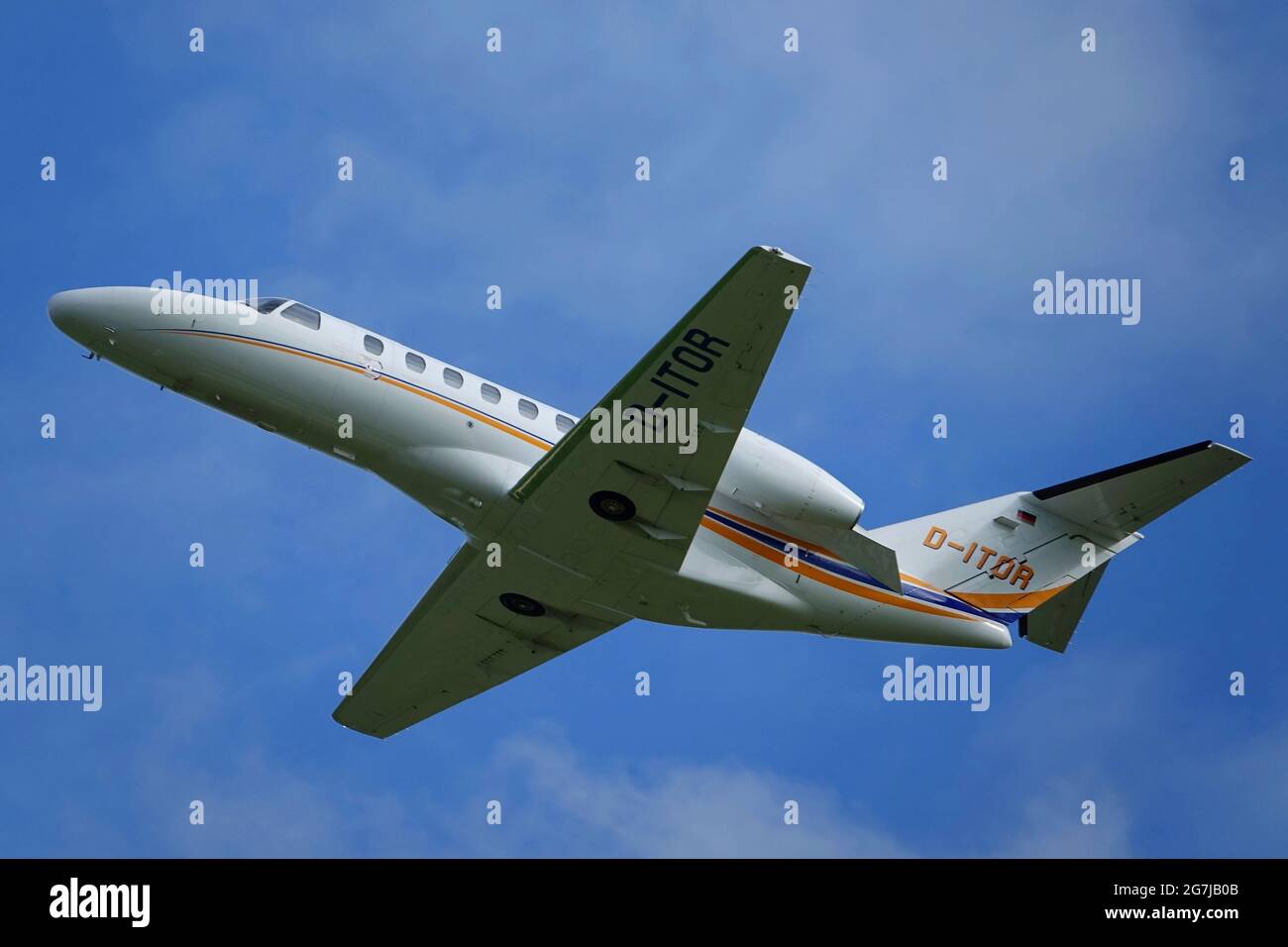 WILHELMSHAVEN, GERMANY - Aug 01, 2020: In flight shot of a white Cessna 525 Citation business jet in front of blue sky Stock Photo