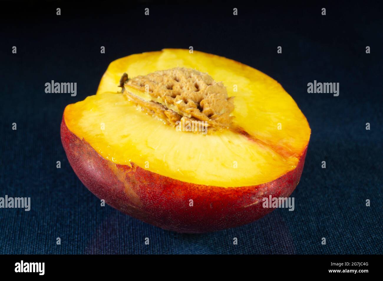 Sliced peach with a nut on the table with a reflection. Food products on a black background Stock Photo