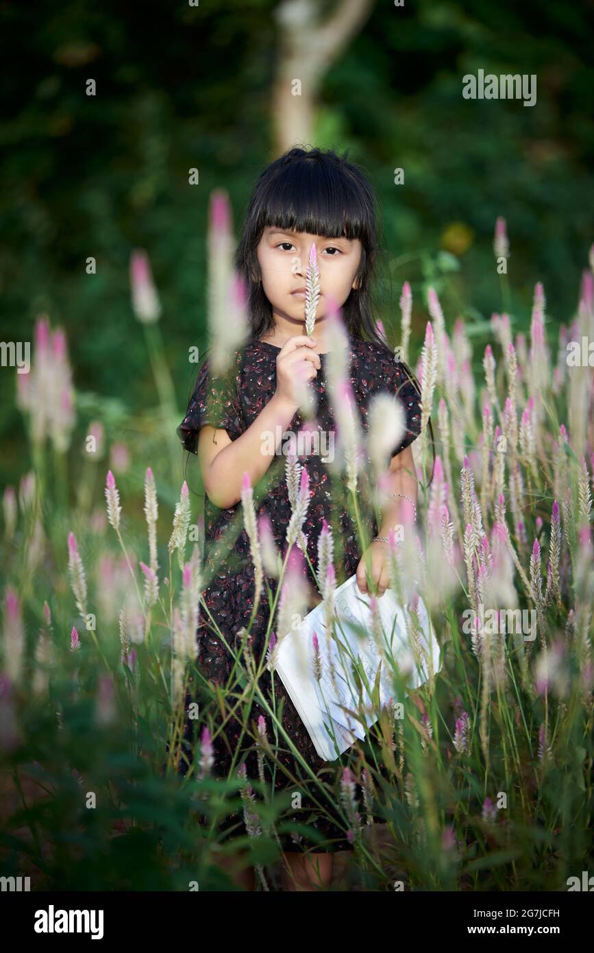 Cute little girl enjoying bloom of wild flowers in the field of meadow ...