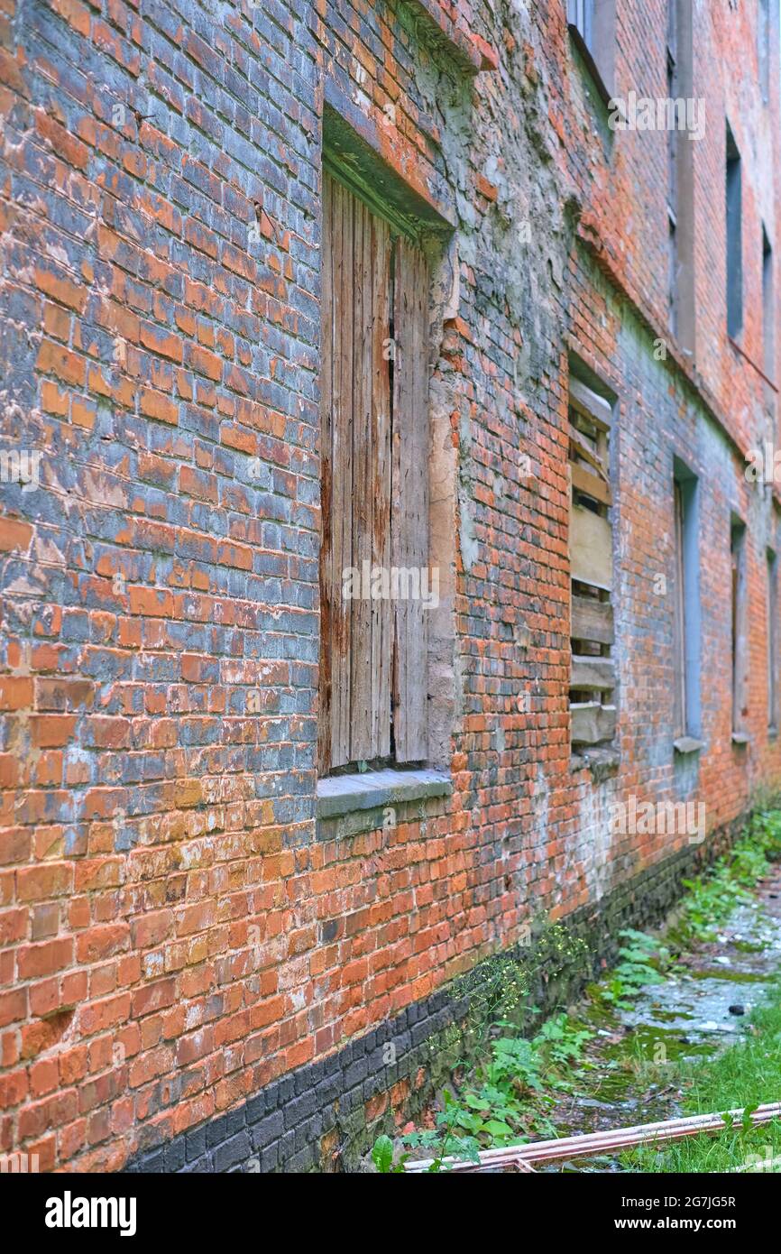 Wall of an abandoned red brick building with boarded up windows Stock ...