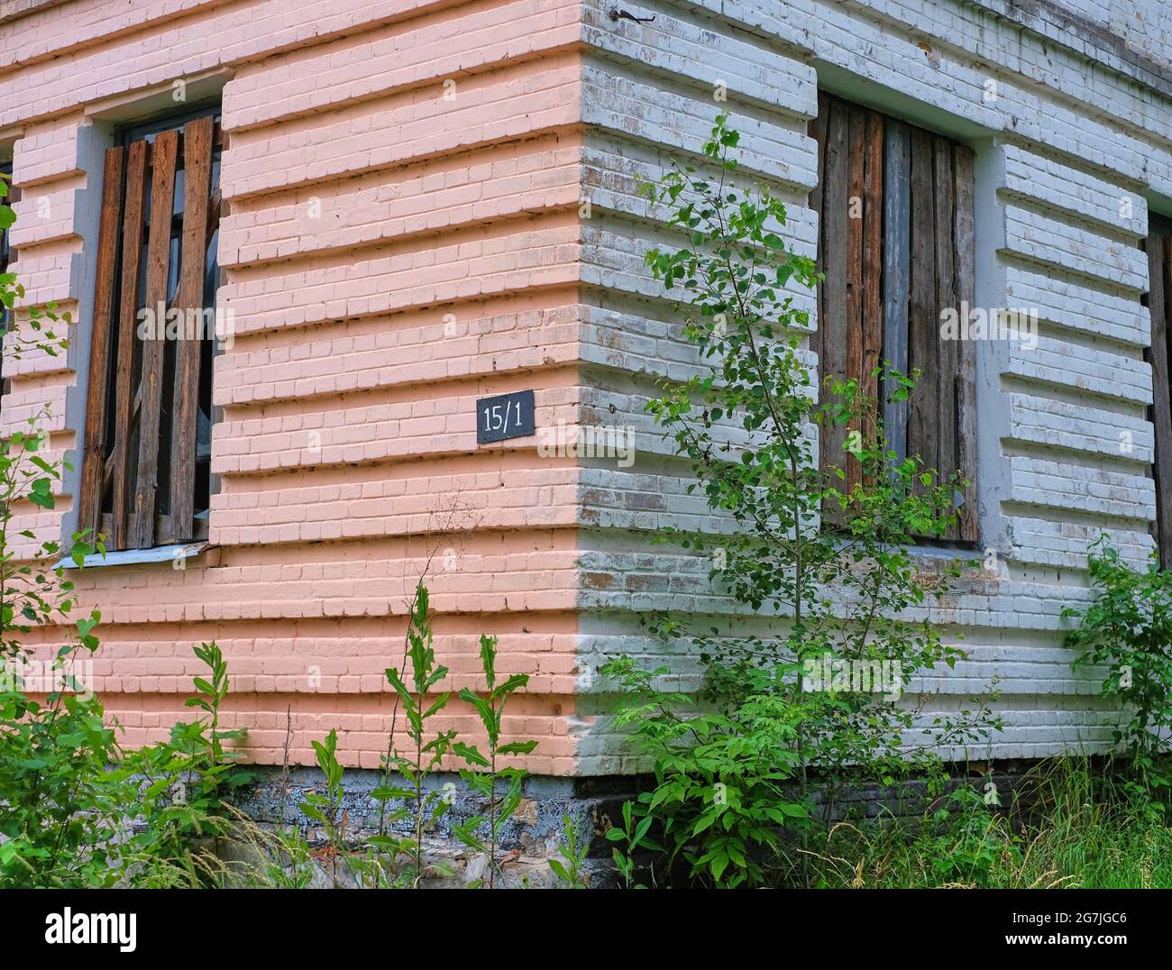 The corner of an abandoned building with hardened windows and house number Stock Photo