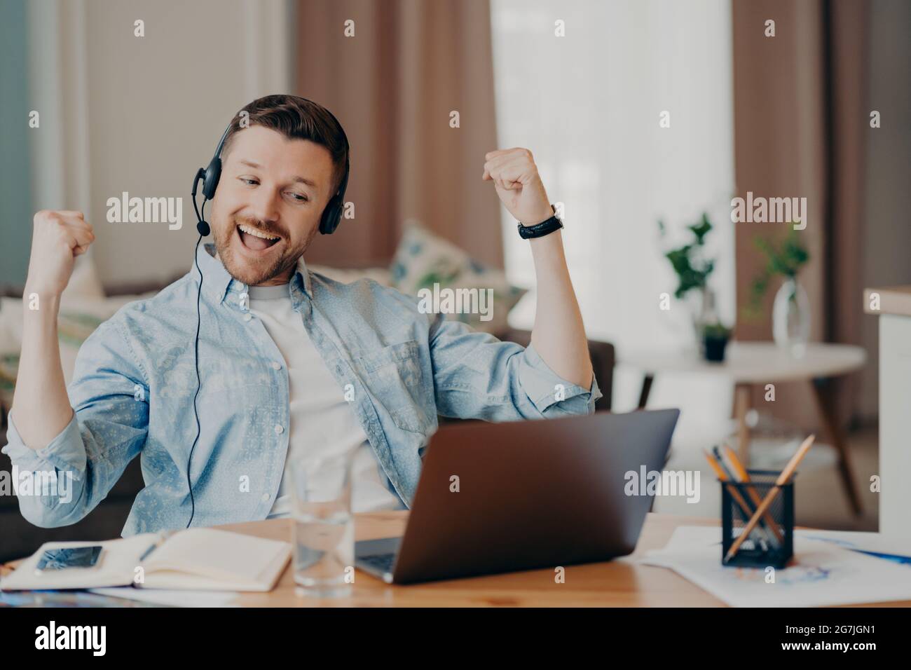 Handsome man enjoying victory while sitting at his workplace at home Stock Photo