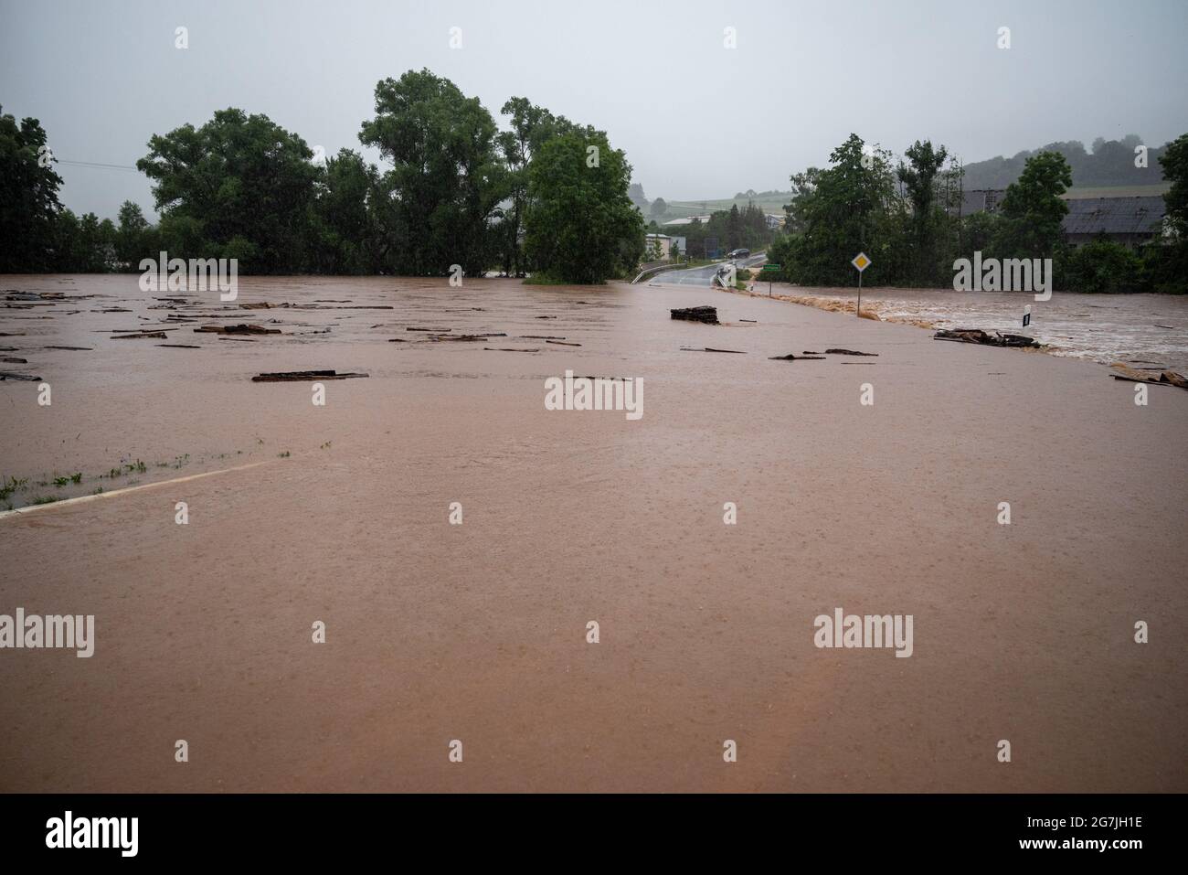 Seffern, Germany. 14th July, 2021. County road 74 between Rittersdorf and Nattenheim is flooded by the Nims. Continuous rainfall has flooded numerous villages and cellars in Rhineland-Palatinate. Credit: Harald Tittel/dpa/Alamy Live News Stock Photo