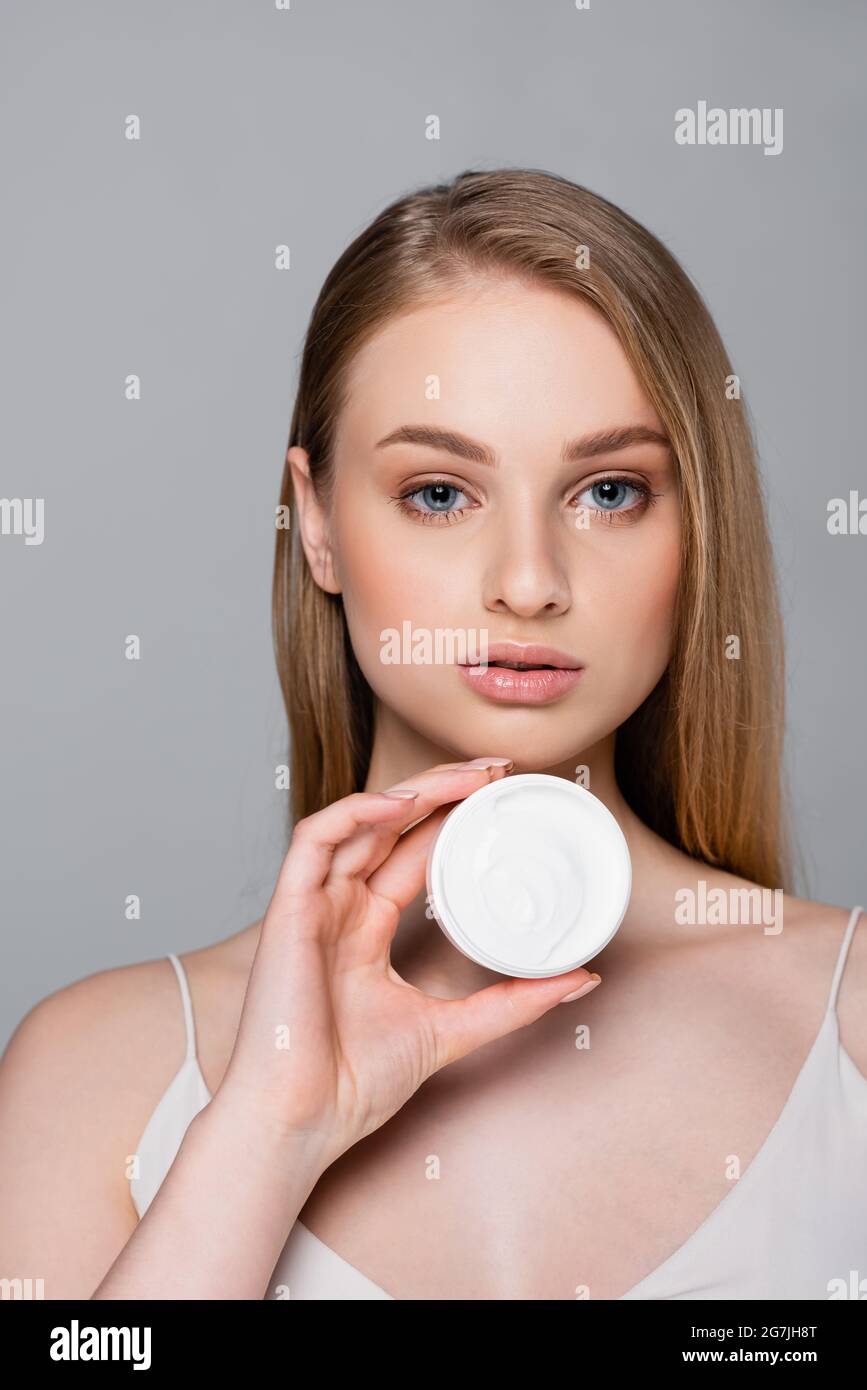 pretty woman holding container with face cream isolated on grey Stock Photo