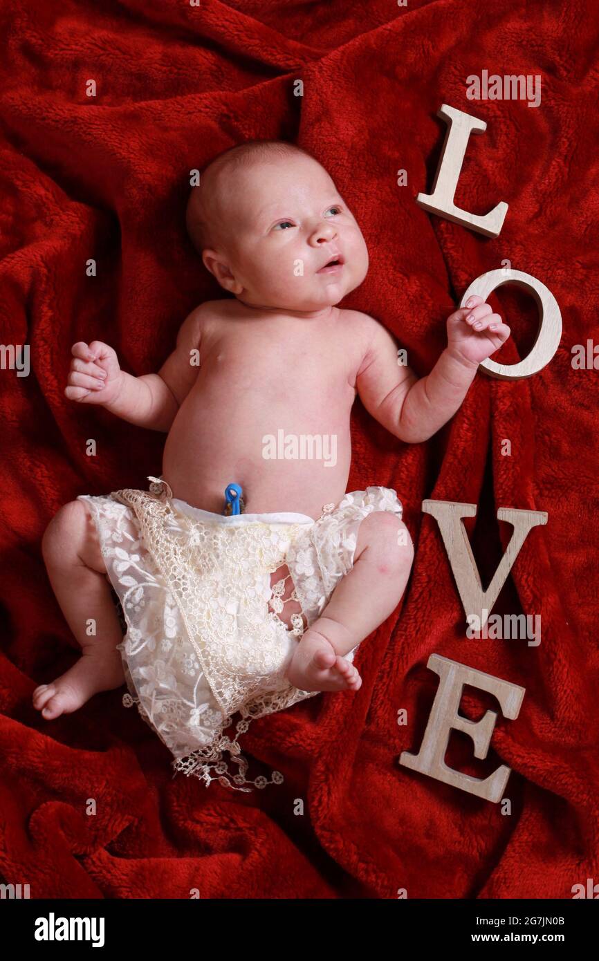 new born baby boy withUmbilical Cord Clamp still attached on red