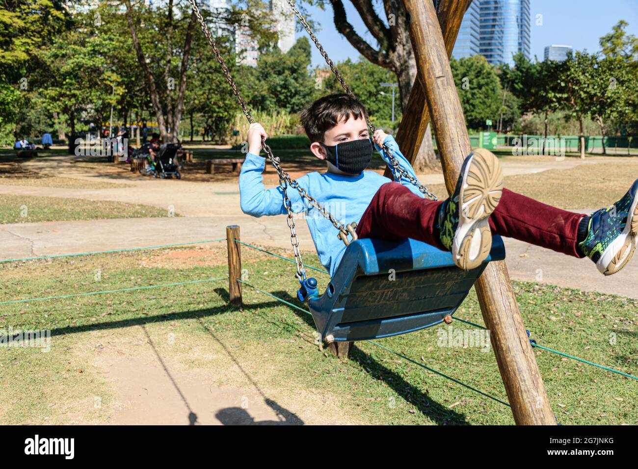8 year old child swinging hard on a swing on a sunny day. Stock Photo