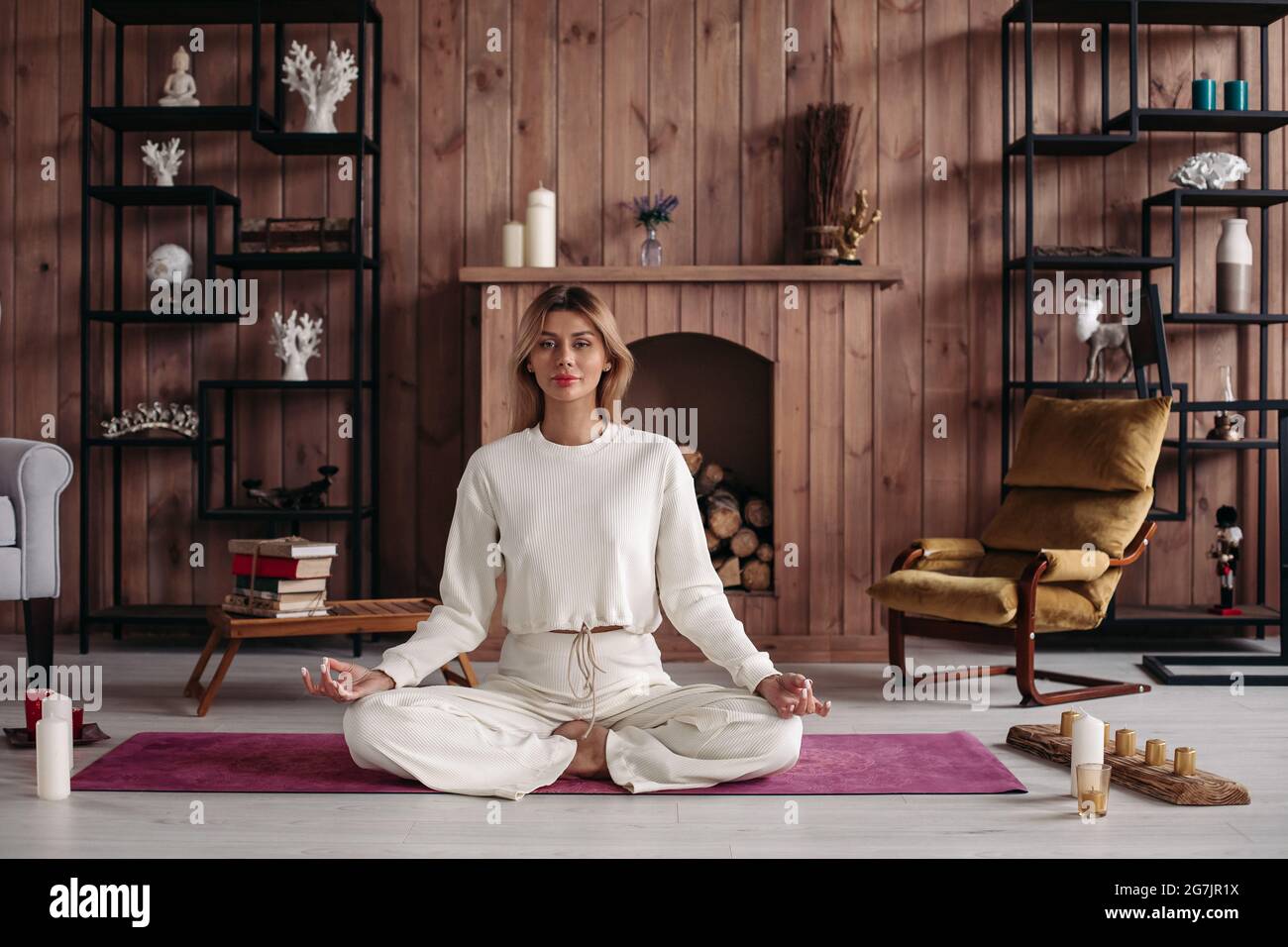 Smiling young girl practicing yoga sitting in lotus pose, meditating in cozy  home interior. Female training for wellness Stock Photo - Alamy