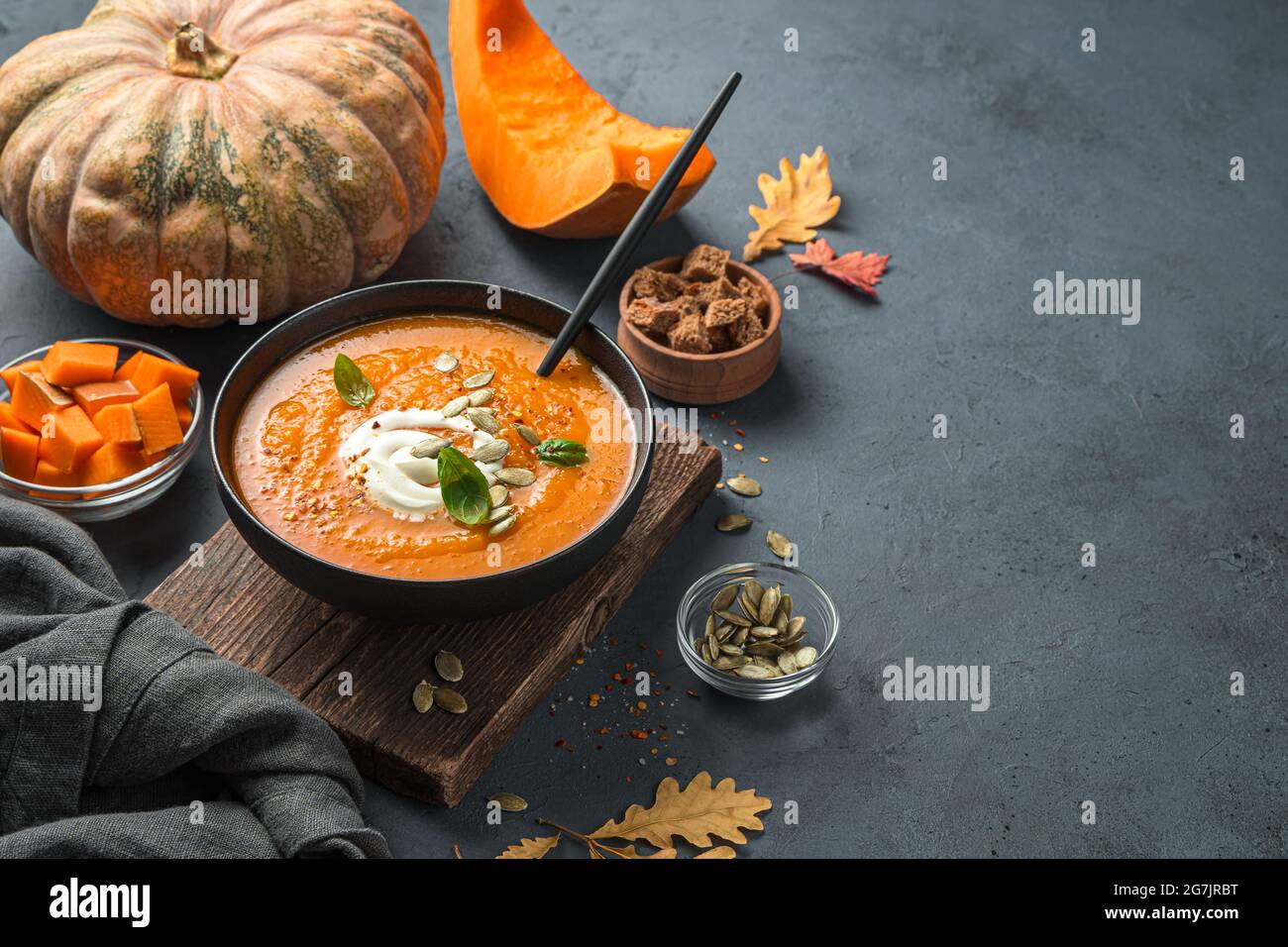 Autumn pumpkin soup cream with cream and pumpkin seeds on a dark blue background. Stock Photo