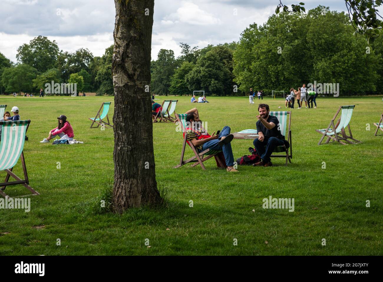 London. UK- 07.11.2021. People relaxing on deck chairs in Hyde Park. Stock Photo