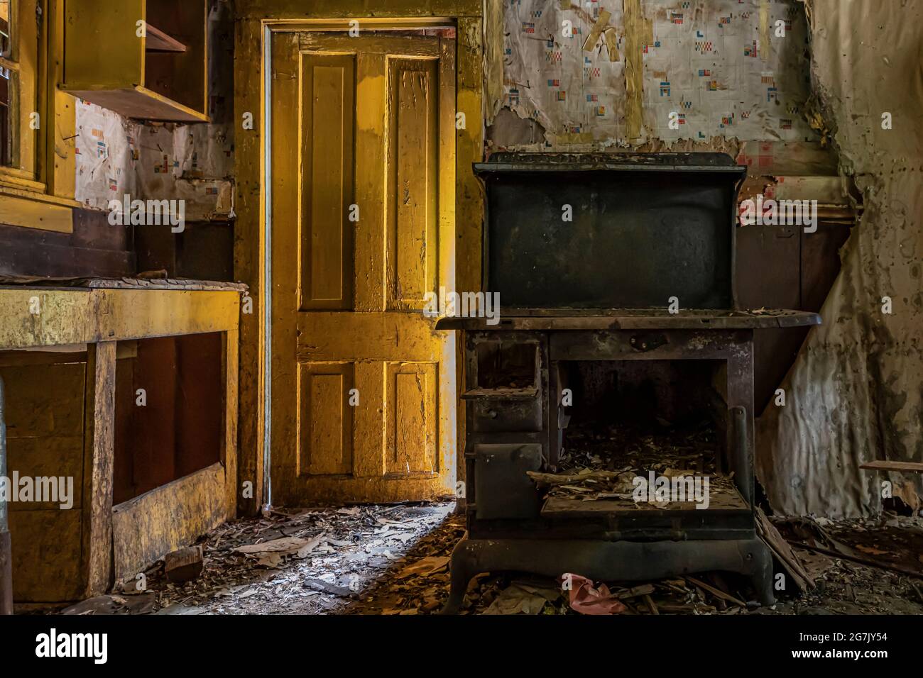 Yellow door and old stove inside old house in Garnet ghost town, a town once home to gold miners and their families, Montana, USA Stock Photo