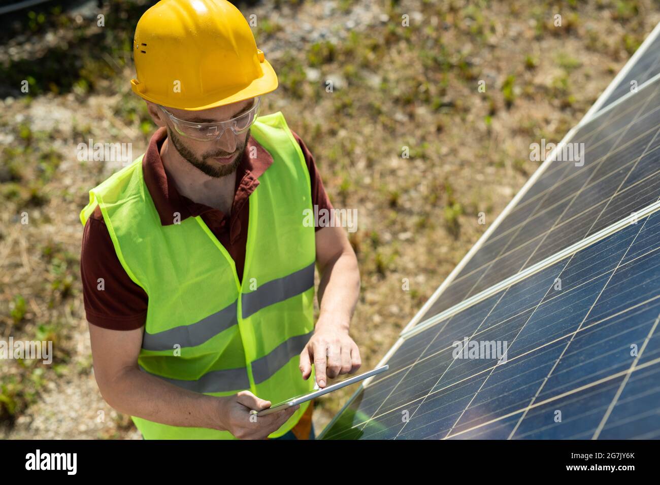 Solar panel mounter in vest, goggles and hardhat checking information on tablet computer Stock Photo