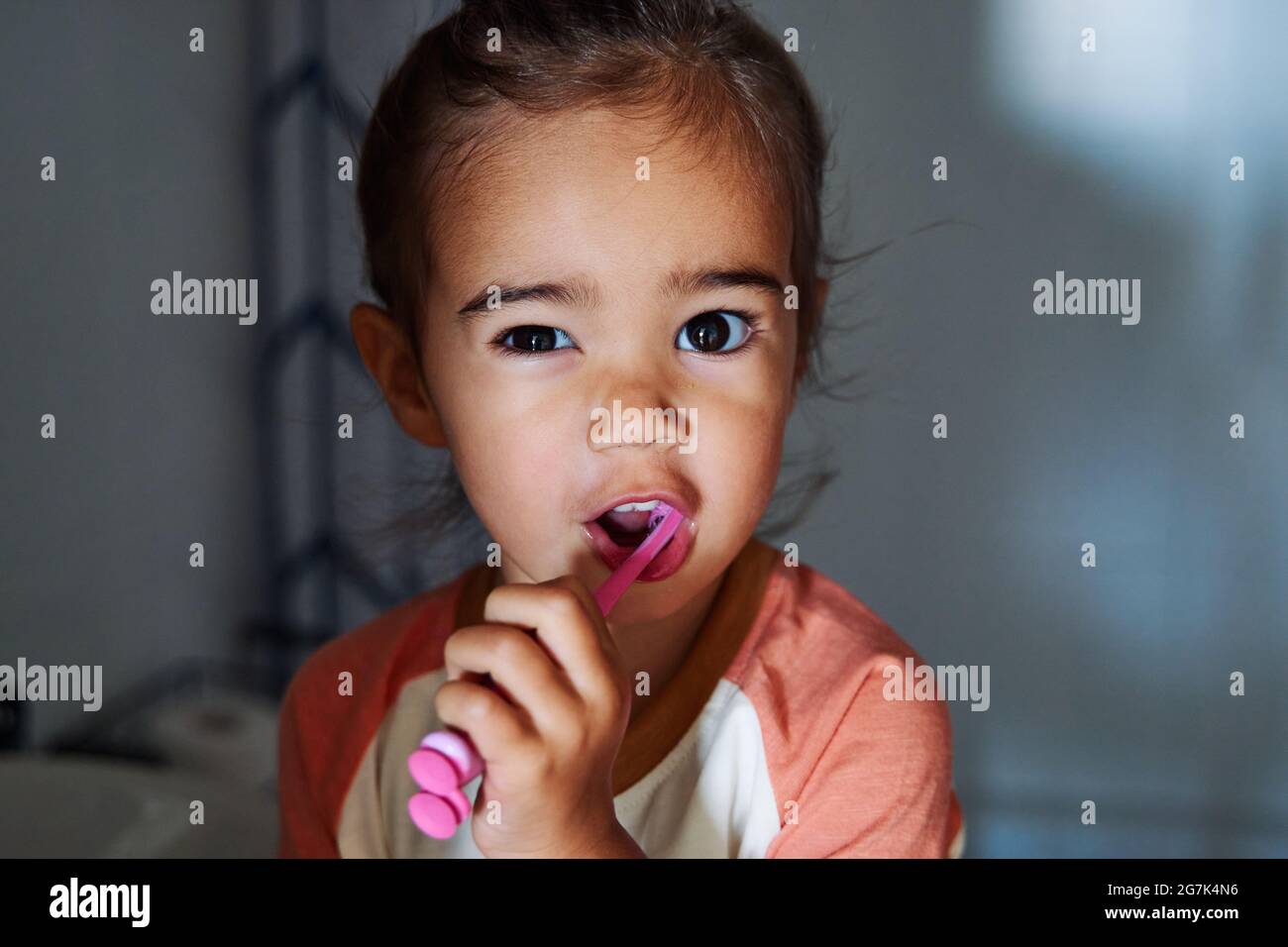 Adorable Spanish baby girl washing her teeth in the bathroom Stock