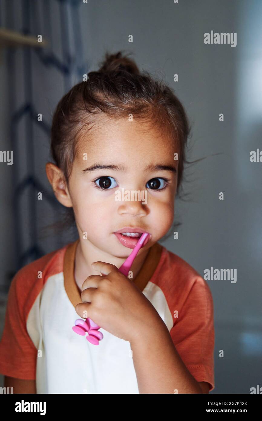 Adorable Spanish baby girl washing her teeth in the bathroom Stock