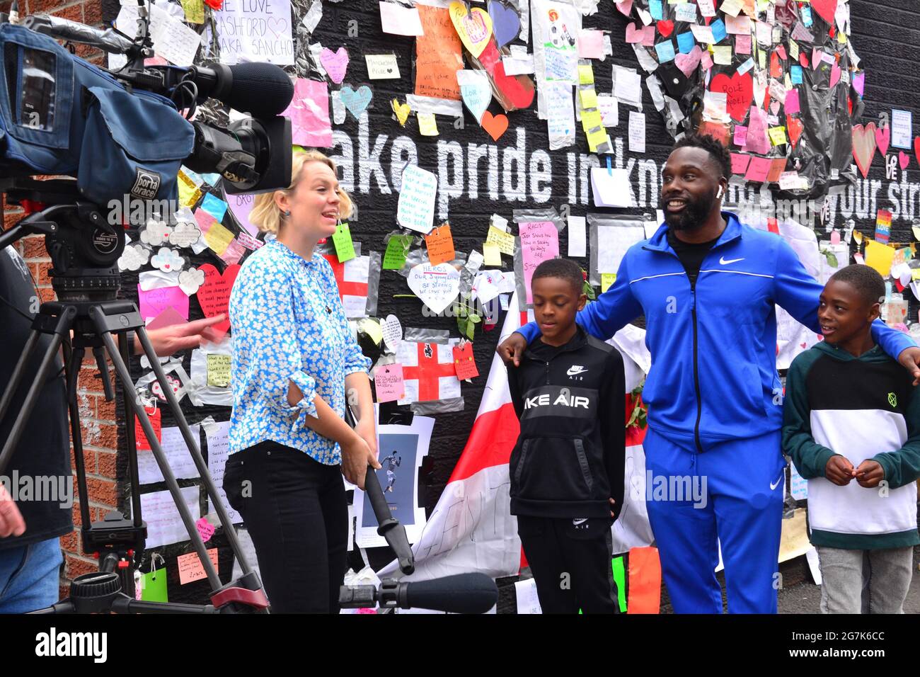 Tru Powell, 36, from Birmingham with sons David,10, and Israel,8, being interviewed by a TV channel at the Marcus Rashford mural in Manchester, UK Stock Photo