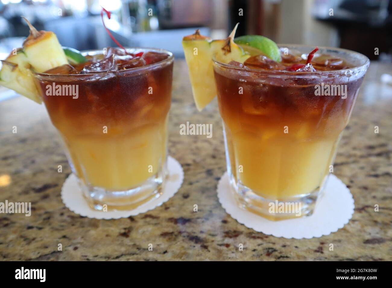 Pair of mai tai cocktail beverages with pineapple garnish at a bar in