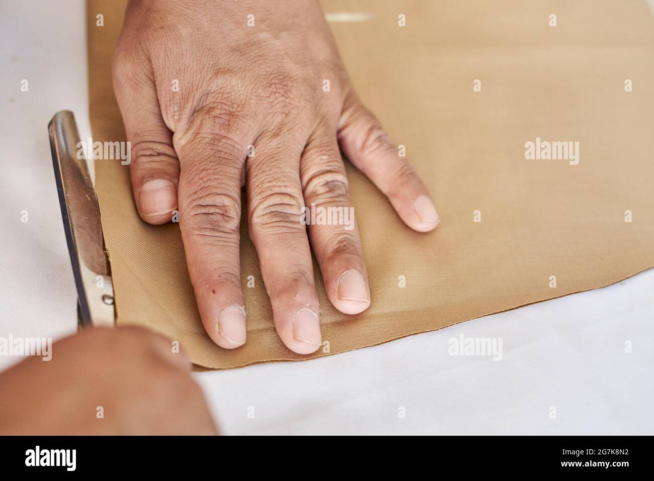 Dressmaker cutting cloth with scissors in a tailor studio Stock Photo ...