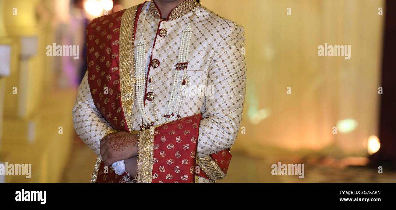 Photo of bride and groom in contrasting outfits with grey sherwani and red  lehenga