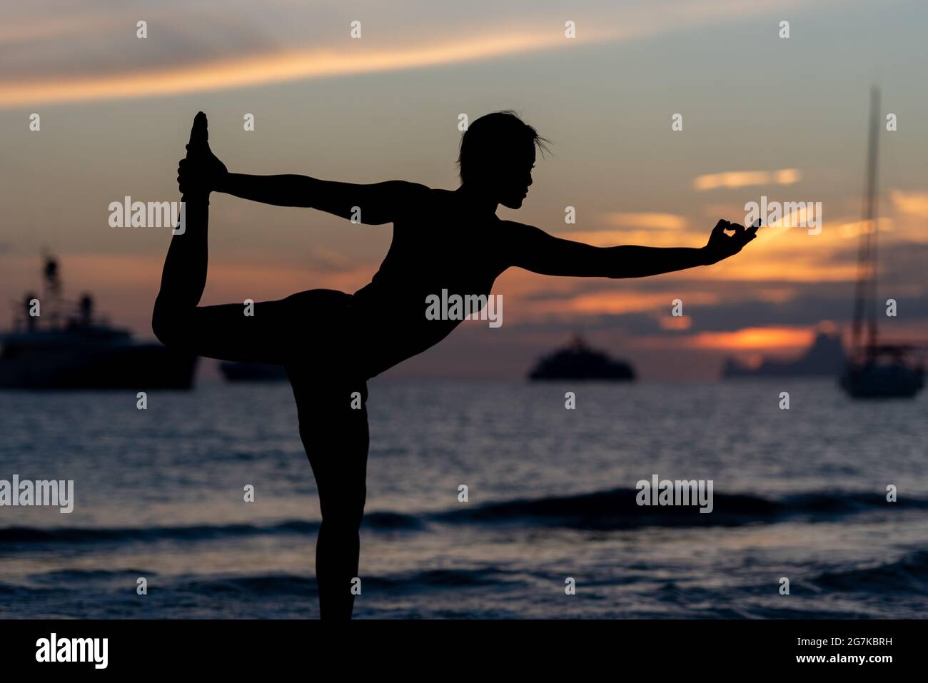Silhouette of Fitness model doing yoga at sunset time. Stock Photo