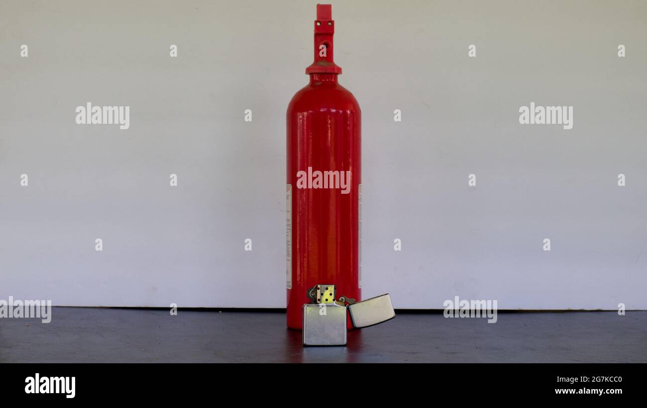A Windproof Lighter Sitting in Front of a Fire Extinguisher Stock Photo