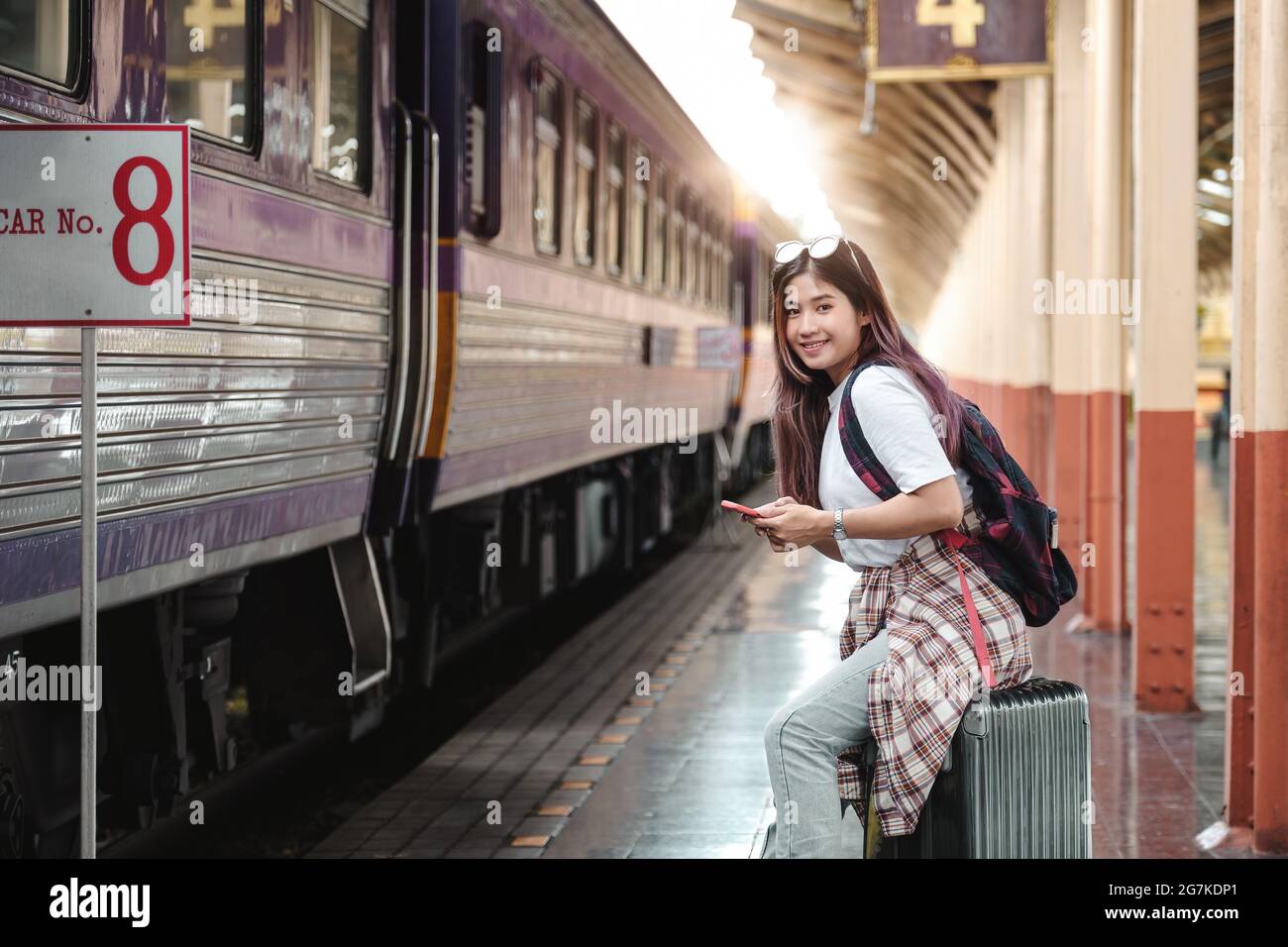 Portrait attraction asian Woman traveler tourist sitting with luggage at train station. Active and travel lifestyle concept. Stock Photo