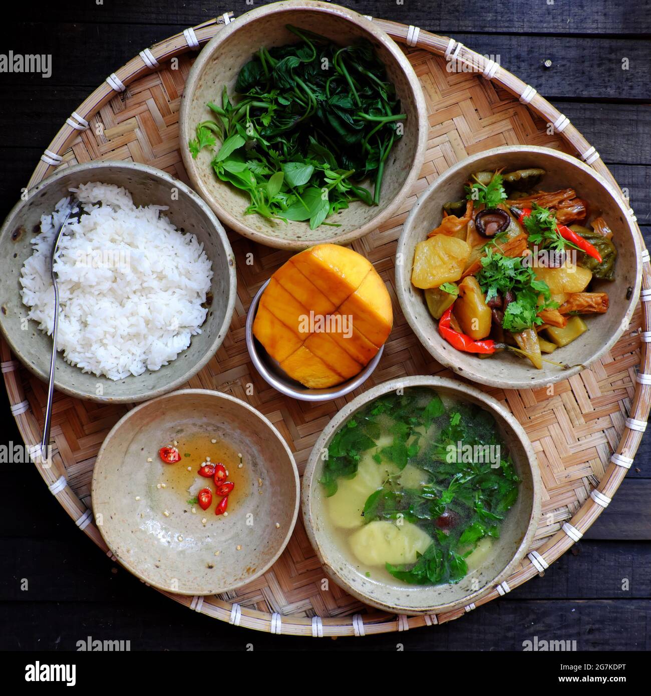 Vietnamese daily meal for lunch, tray of rice dish with boiled sweet potato buds, pineapple soup, tofu skin, pineapple, mushrooms cook with sauce Stock Photo