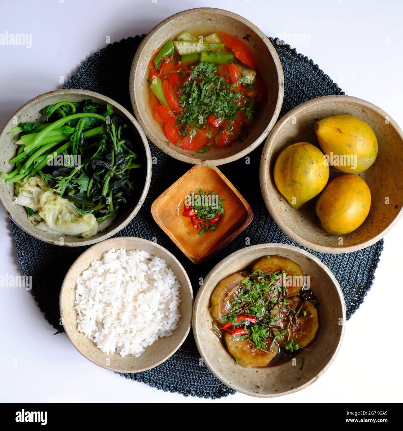 Vietnamese vegan meal for lunch time with simple ingredient, gourd cook with sauce, boiled vegetable, tomato and okra soup, frugal healthy eating on w Stock Photo