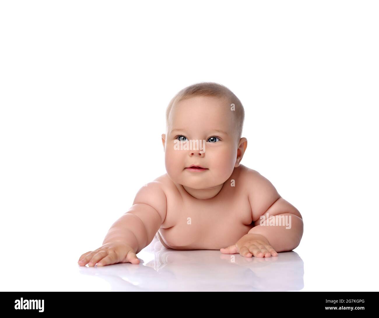 Healthy infant child baby girl kid in diaper is lying on her stomach holding arm outstretched, slapping on floor  Stock Photo
