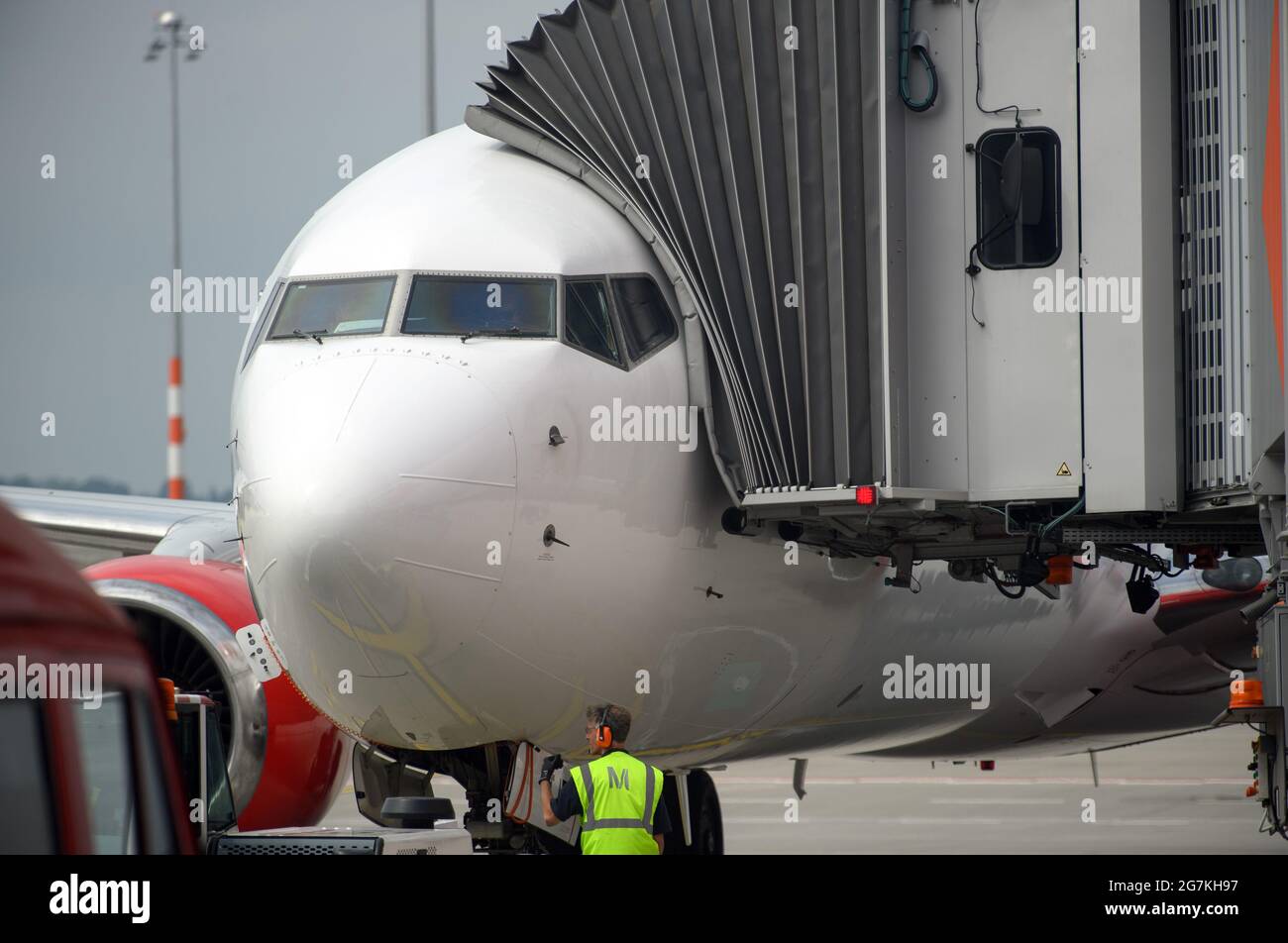 14 July 2021, Brandenburg, Schönefeld: An employee of WISAG Aviation stands  on the apron of BER "Willy Brandt" Airport in front of an aircraft of the  Turkish airline Corendon Airlines. During the