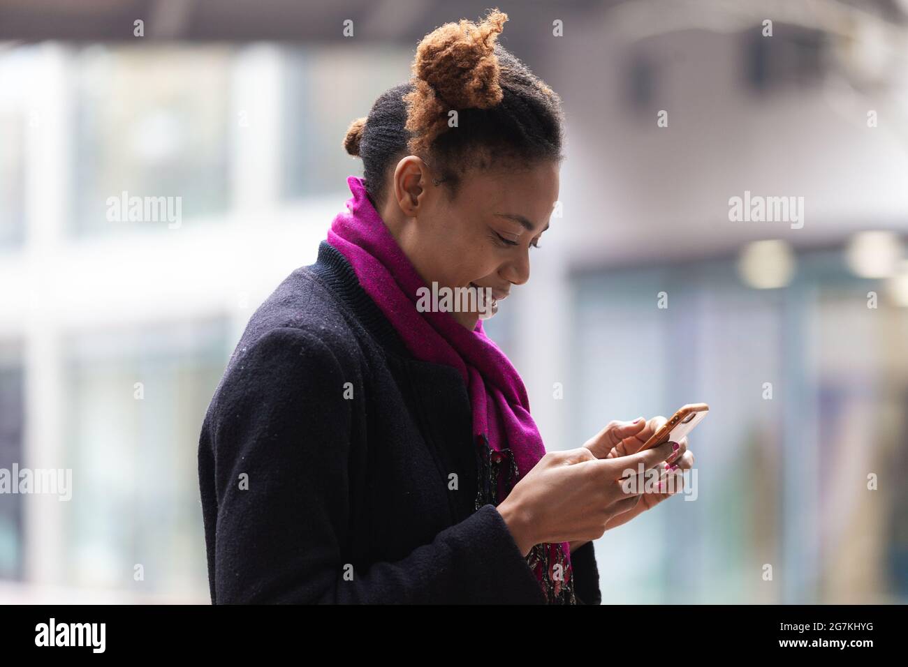 close up of happy African woman looking at mobile phone in hand in  city street Stock Photo