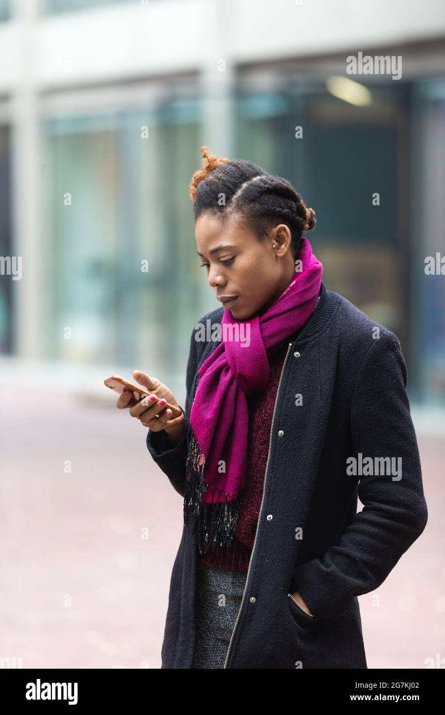 close up of happy African woman looking at mobile phone please hand in your city street Stock Photo