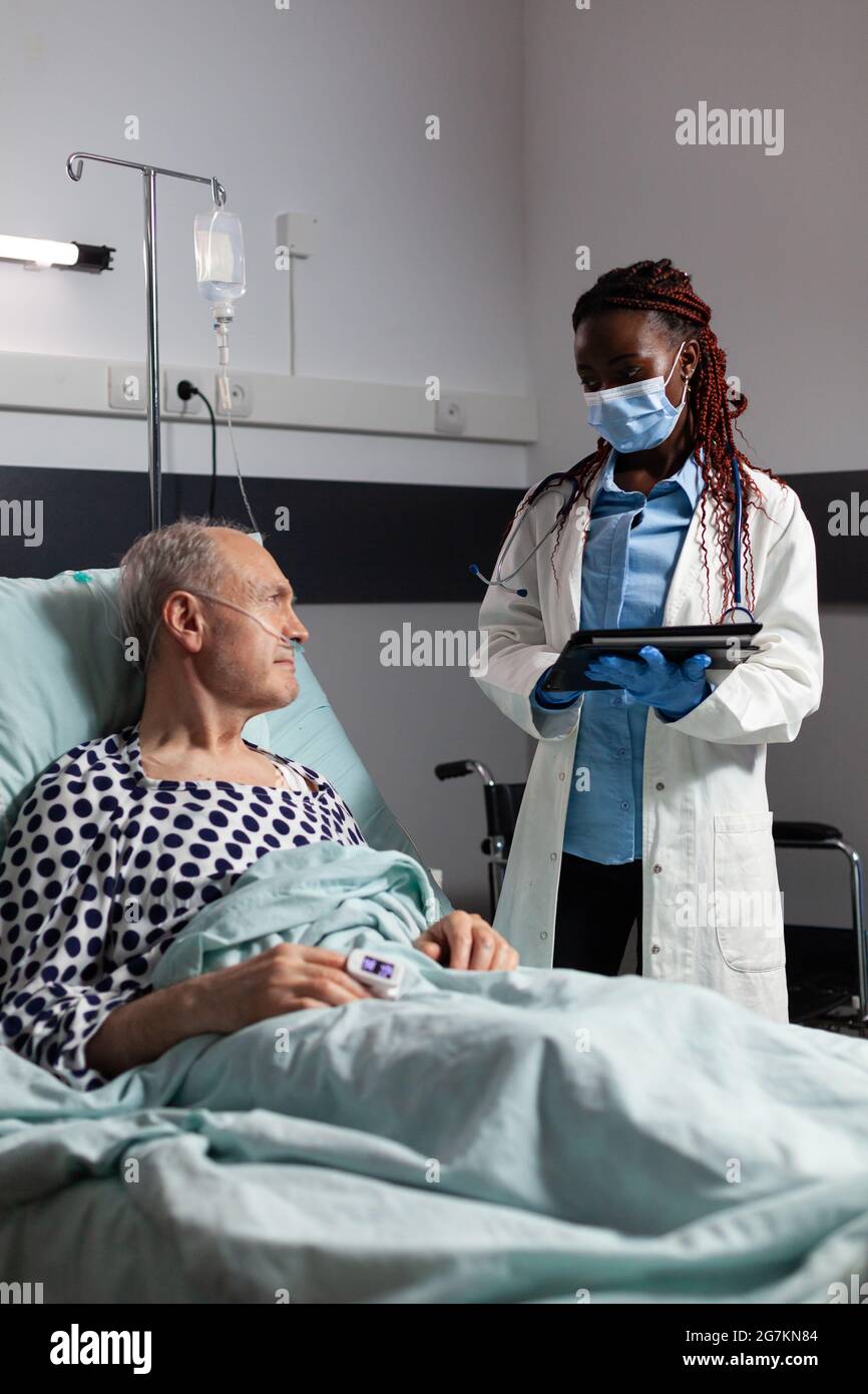 African American Doctor With Chirurgical Mask In Hospital Room Discussing Diagnosis And 