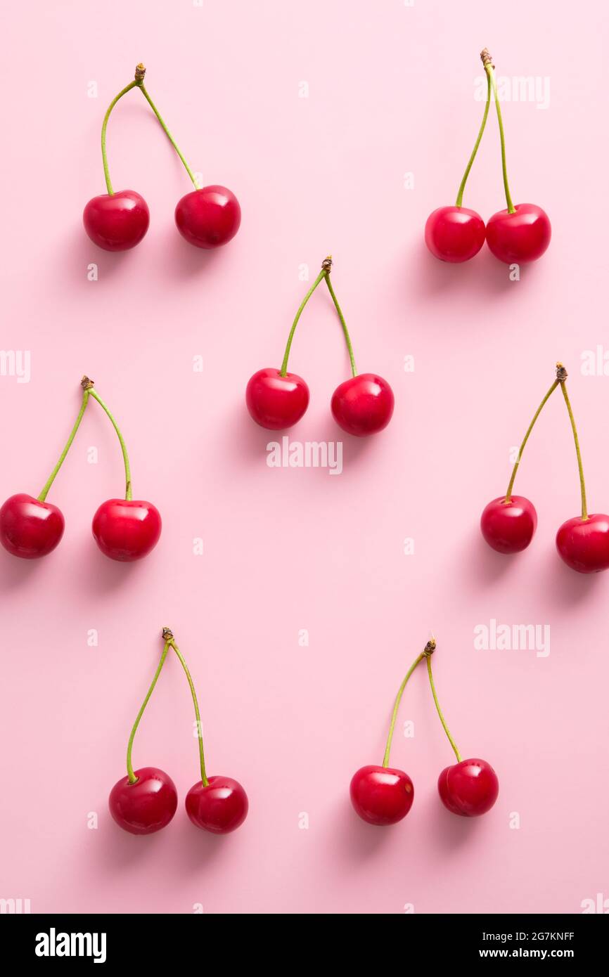 Ripe red cherries on pink background. Flat lay, top view Stock Photo ...