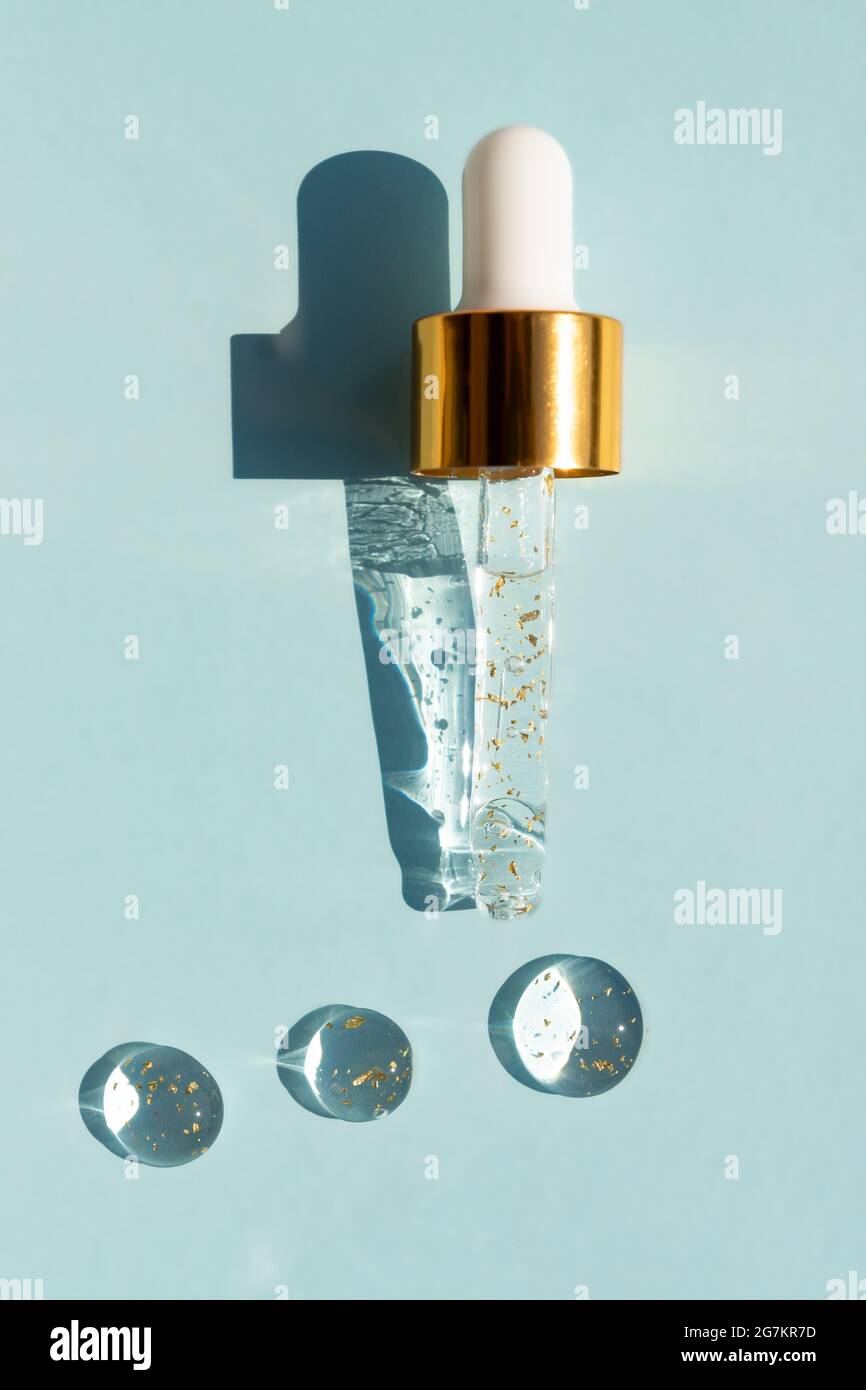 Liquid serum and dropper on a blue background top view. 24k gold Serum drops  in the form of a circle with a pipette Stock Photo - Alamy