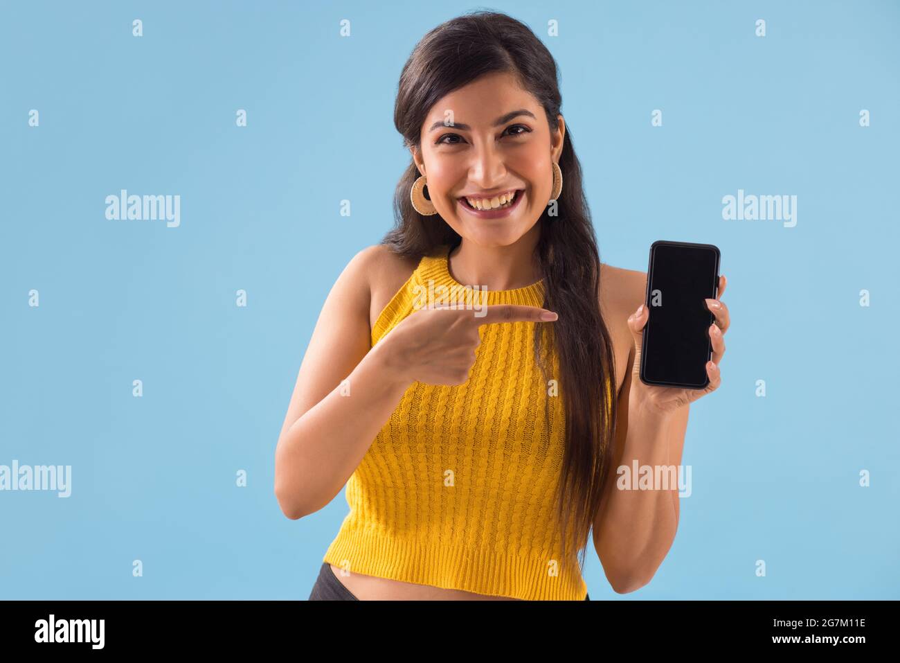 A young woman pointing towards her mobile phone. Stock Photo