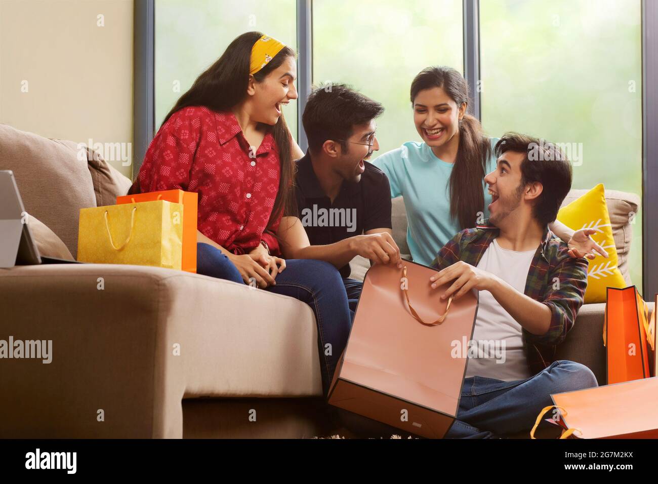A Group of youngsters talking happily in living room after a shopping spree. Stock Photo