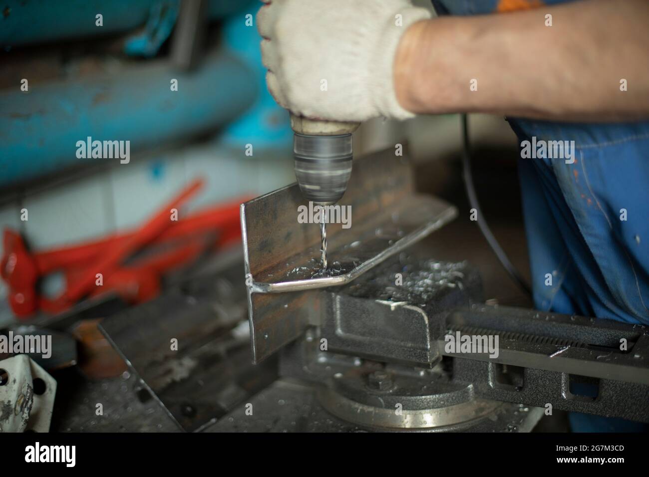 Drills metal with a drill. The man is working. Drilling holes in steel
