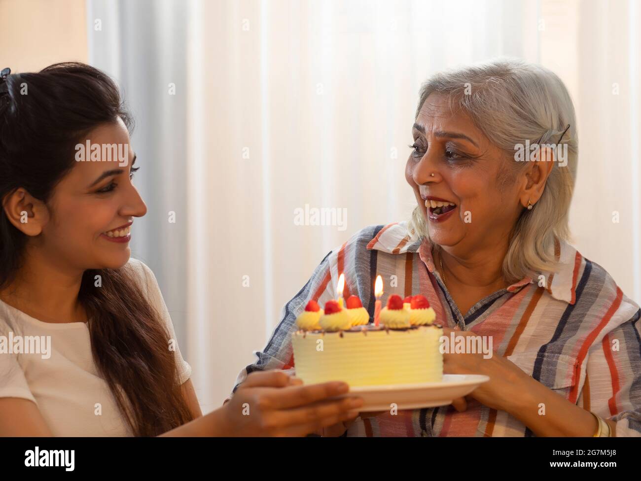 A YOUNG DAUGHTER PRESENTING MOTHER WITH A CAKE Stock Photo