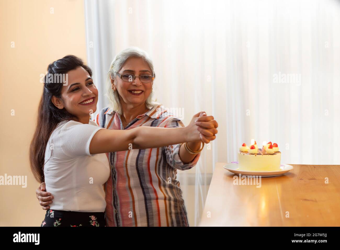 A DAUGHTER AND MOTHER ENJOYING AND DANCING TOGETHER WHILE CELEBRATING BIRTHDAY Stock Photo