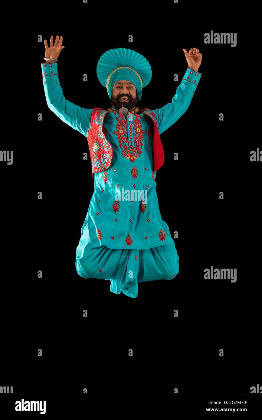 A Bhangra Dancer jumping with hands up to perform a dance step